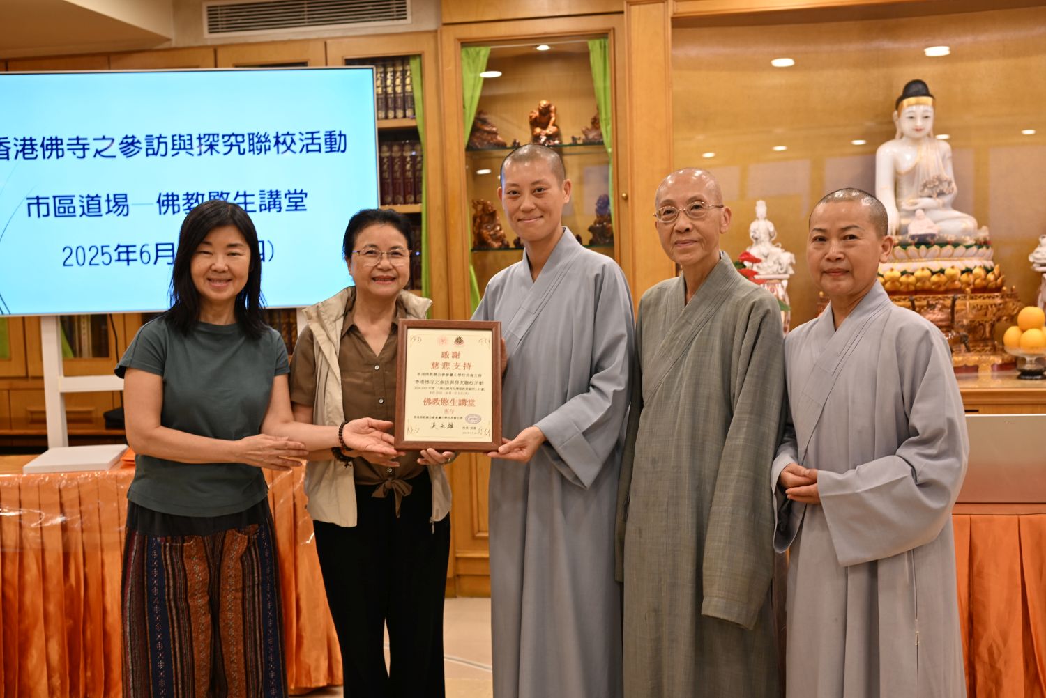 佛教愍生講堂寬廣法師（中）、寬仁法師（右二）和寬乘法師（右一）從佛化德育及價值教育顧問黃鳳鳴女士（左二）和梁鳳燕女士（左一）手中接過感謝狀。