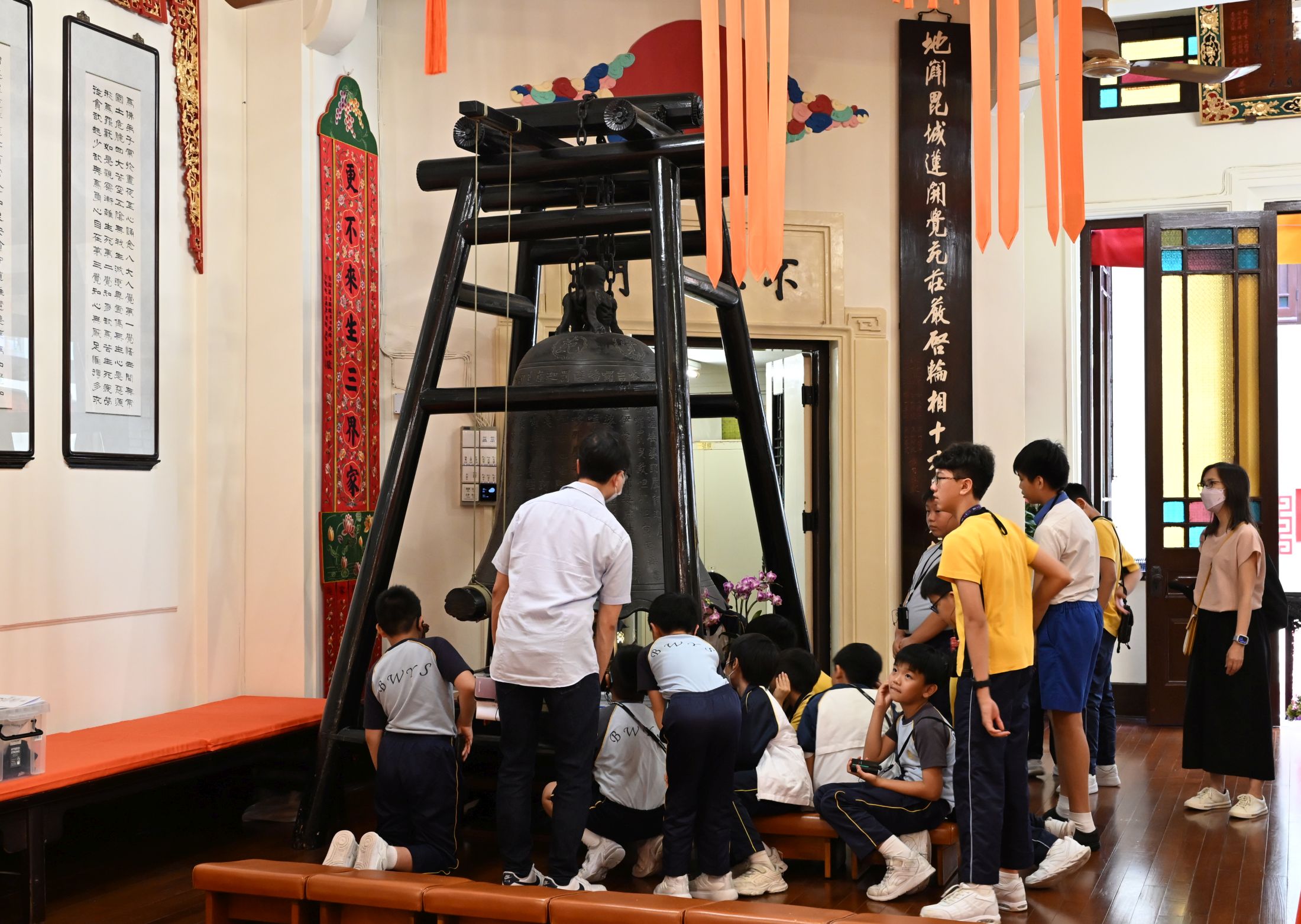 學生觀賞大雄寶殿內的銅鐘。該銅鐘歷史悠久，1933年由何東與張蓮覺居士捐獻，靄亭法師與林楞真居士監造。